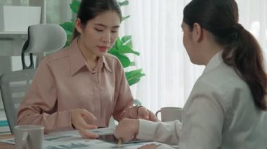 Ofis çalışma alanında birlikte çalışan iki genç hevesli iş kadını. Genç meslektaşlar tartışırken ve dizüstü bilgisayar kullanırken. Modern ofis çalışanları masada birlikte oturuyorlar..