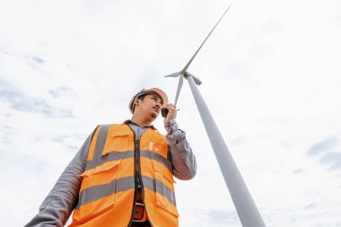 Kırsal kesimdeki bir tepenin tepesinde ya da dağda rüzgar çiftliğinde çalışan bir mühendis. Yenilenebilir ve sürdürülebilir enerjinin gelecekteki üretimi için yenilikçi bir ideal. Rüzgar türbininden enerji üretimi.