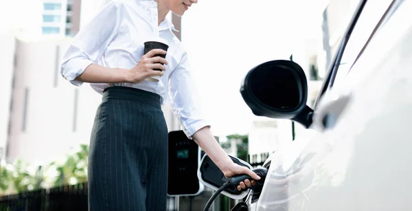 Zbliżenie Businesswoman Trzyma Kawę Włożyć Ładowarkę Pojazdu Elektrycznego Publicznej Stacji — Zdjęcie stockowe