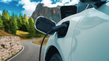 Elektrikli araç konsepti, yeşil çevre için yenilenebilir ve temiz enerjiyle çalışan EV otomobilinin varış noktasına ulaşmadan önce ormandaki şarj istasyonunun enerjisini şarj etmek için durur..