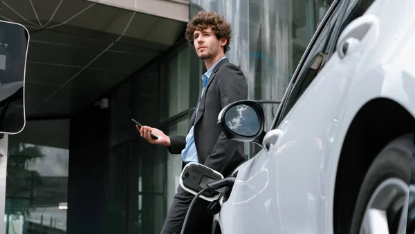 Progressive Businessman Talking Phone Leaning Electric Car Recharging Public Charging — Foto Stock