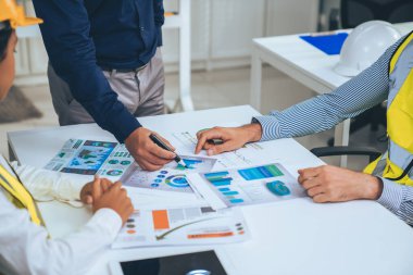 Engineers and competent employer discussing plans and blueprints together with tablet in the office. Concept of team contribution of ideas for engineering project.