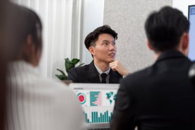 Harmony in office concept as business people analyzing dashboard paper together in workplace. Young colleagues give ideas at manager desk for discussion or strategy planning about project.