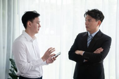 Manager advising guiding younger colleague with tablet in workplace. Couple businesspeople in formal wear working together on financial strategy as concept of teamwork and harmony in office.