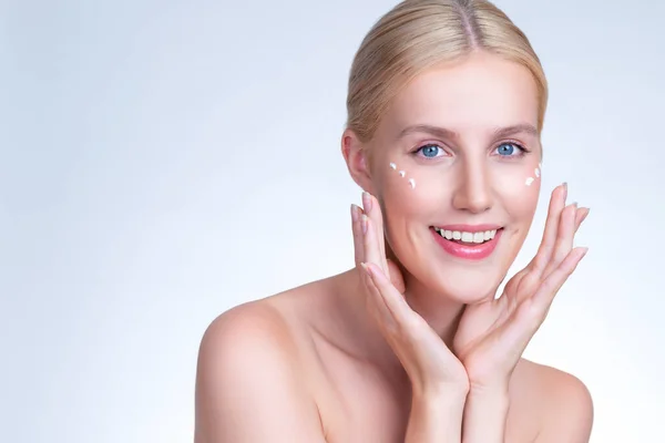 Stock image Personable beautiful perfect clean skin soft makeup woman finger applying moisturizer cream on her face under contour eye for anti aging wrinkle. Facial skin rejuvenation in isolated background.