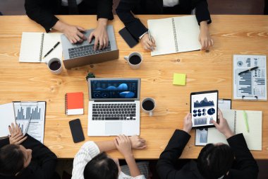 Top view manager or office worker give presentation in harmony conference room to business colleague, BI data dashboard on screen and pile of financial analyzed data reports on meeting table.