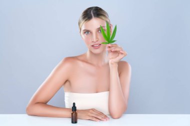 Alluring portrait of beautiful woman in isolated holding green leaf with marijuan extracted bottle for skincare treatment product. Cannabis CBD oil for cosmetology and beauty concept.