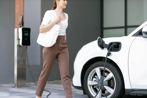 Progressive Asian Woman Electric Car Home Charging Station Concept Use — Stok fotoğraf