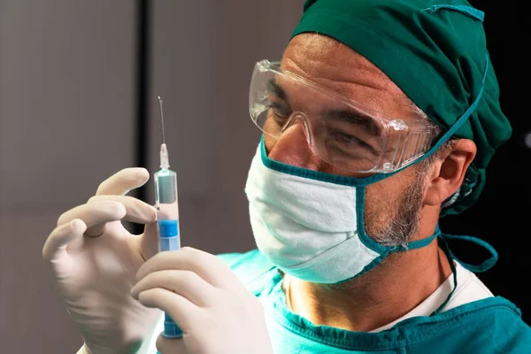 外科医生在无菌手术室用医用药瓶充填注射器进行外科手术 全副武装的医生为他的病人准备麻醉注射 — 图库照片