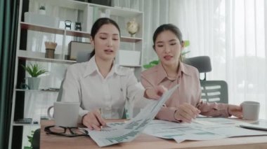 Ofis çalışma alanında birlikte çalışan iki genç hevesli iş kadını. Genç meslektaşlar tartışırken ve dizüstü bilgisayar kullanırken. Modern ofis çalışanları masada birlikte oturuyorlar..