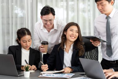 Harmony in office concept as business people analyzing dashboard paper together in workplace. Young colleagues give ideas at manager desk for discussion or strategy planning about project.