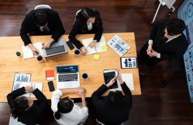 Top view manager or office worker give presentation in harmony conference room to business colleague, BI data dashboard on screen and pile of financial analyzed data reports on meeting table.