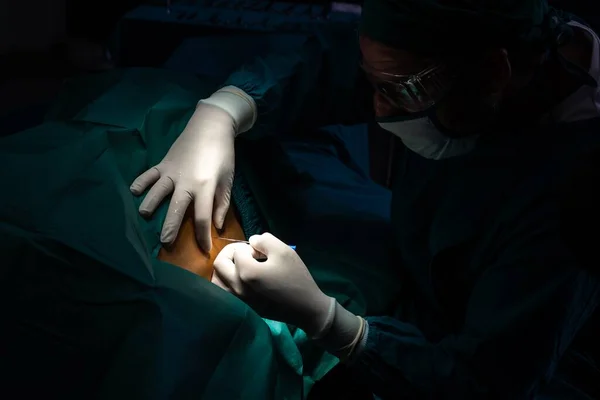 在用现代外科设备进行无菌手术室的手术前 外科医生用注射器向病人注射麻醉 由专业和自信的外科医生进行的医疗手术 — 图库照片