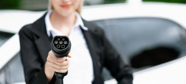 stock image Blur closeup businesswoman hand holding and pointing an EV plug at camera for electric vehicle as progressive idea of alternative sustainable clean and green energy for environmental concern.