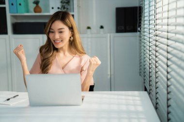 A young female employee receives a promotion, good news or finished her task and overjoyed for being a competent worker.