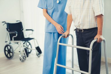 Physiotherapist assists contented senior man on folding walker. Recuperation for elderly, seniors care, nursing home.