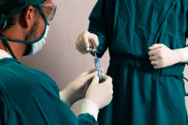 外科医生在无菌手术室用药瓶充填注射器进行外科手术 并配备辅助护士 全副武装的医生和医护人员准备麻醉注射 — 图库照片