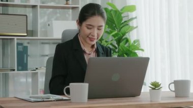 Ofiste çalışan ve dizüstü bilgisayar yazan hevesli bir iş kadını. Masasında oturmuş laptopla çalışan güzel bir ofis hanımı..