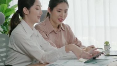 Ofis çalışma alanında birlikte çalışan iki genç hevesli iş kadını. Genç meslektaşlar tartışırken ve dizüstü bilgisayar kullanırken. Modern ofis çalışanları masada birlikte oturuyorlar..