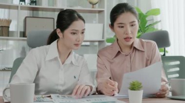 Ofis çalışma alanında birlikte çalışan iki genç hevesli iş kadını. Genç meslektaşlar tartışırken ve dizüstü bilgisayar kullanırken. Modern ofis çalışanları masada birlikte oturuyorlar..