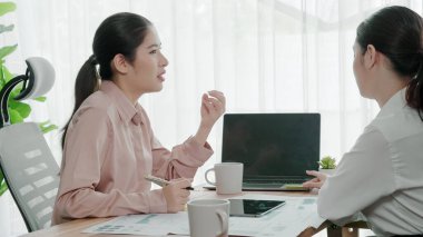 Ofis çalışma alanında birlikte çalışan iki genç hevesli iş kadını. Genç meslektaşlar tartışırken ve dizüstü bilgisayar kullanırken. Modern ofis çalışanları masada birlikte oturuyorlar..