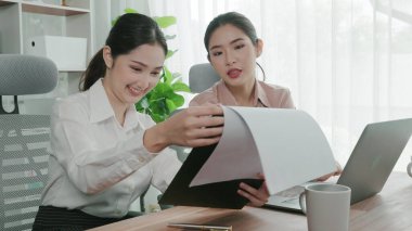 Ofis çalışma alanında birlikte çalışan iki genç hevesli iş kadını. Genç meslektaşlar tartışırken ve dizüstü bilgisayar kullanırken. Modern ofis çalışanları masada birlikte oturuyorlar..