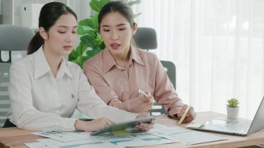 Ofis çalışma alanında birlikte çalışan iki genç hevesli iş kadını. Genç meslektaşlar tartışırken ve dizüstü bilgisayar kullanırken. Modern ofis çalışanları masada birlikte oturuyorlar..