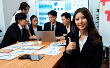 Focus portrait of female manger, businesswoman in the harmony meeting room with blurred of colleagues working together, analyzing financial paper report and dashboard data on screen in background.