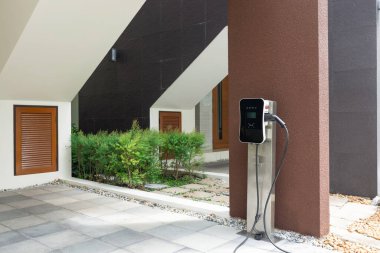 Progressive green energy-powered charging station concept for electric vehicle connected to home charging station at the garage or backyard. Eco friendly rechargeable car powered by clean energy.