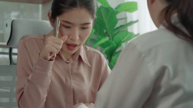 Ofis çalışma alanında birlikte çalışan iki genç hevesli iş kadını. Genç meslektaşlar tartışırken ve dizüstü bilgisayar kullanırken. Modern ofis çalışanları masada birlikte oturuyorlar..