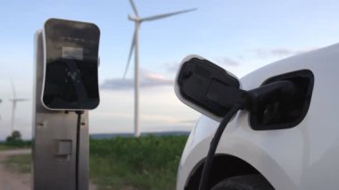 Çevreyi korumak için rüzgar türbininden yeşil ve yenilenebilir enerjiyle çalışan şarj istasyonunda şarj edilen gelişmiş gelecek enerji altyapısı konsepti.