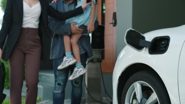 年富力强的年轻父母和女儿住在有电动汽车和电动汽车充电站的家里 促进健康环境的电动汽车的绿色清洁能源 — 图库视频影像