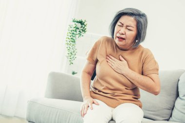 An agonizing elderly woman is experiencing chest pain. Medical attention, senior care service.