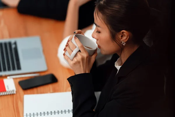 Businesswoman take coffee break, leisure in office after planning strategy, working in office for concept of harmony in workspace concept. Business office worker sitting professional meeting table.