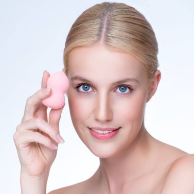 Closeup personable beautiful natural soft makeup woman using powder puff for facial makeup concept. Cushion foundation applying on young girl face in isolated background.