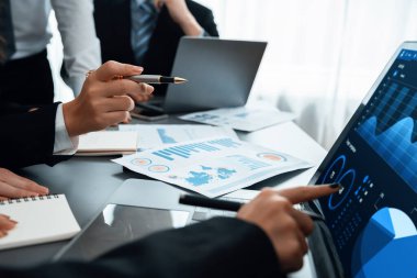 İş adamlarıyla toplantı masasına yakın çekim. İş pazarlama stratejisini analiz ediyorlar. Elleri dizüstü bilgisayarla çalışıyorlar..
