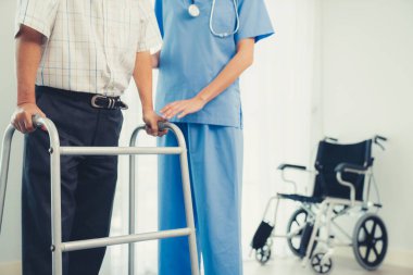 Physiotherapist assists contented senior man on folding walker. Recuperation for elderly, seniors care, nursing home.