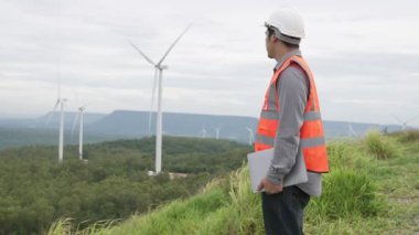 Kırsal kesimdeki bir tepenin tepesinde ya da dağda rüzgar çiftliğinde çalışan bir mühendis. Yenilenebilir ve sürdürülebilir enerjinin gelecekteki üretimi için yenilikçi bir ideal. Rüzgar türbininden enerji üretimi.