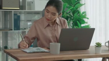 Ofiste çalışan ve dizüstü bilgisayar yazan hevesli bir iş kadını. Masasında oturmuş laptopla çalışan güzel bir ofis hanımı..