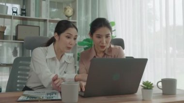 Ofis çalışma alanında birlikte çalışan iki genç hevesli iş kadını. Genç meslektaşlar tartışırken ve dizüstü bilgisayar kullanırken. Modern ofis çalışanları masada birlikte oturuyorlar..