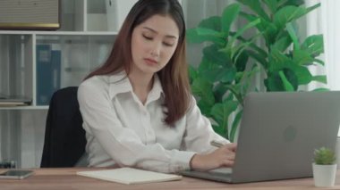 Ofiste çalışan ve dizüstü bilgisayar yazan hevesli bir iş kadını. Masasında oturmuş laptopla çalışan güzel bir ofis hanımı..