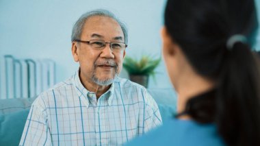 A young female doctor inquires about personal information of a contented senior at home. Medical care for the elderly, elderly illness, and nursing homes, home care.