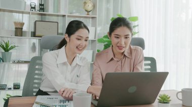 Ofis çalışma alanında birlikte çalışan iki genç hevesli iş kadını. Genç meslektaşlar tartışırken ve dizüstü bilgisayar kullanırken. Modern ofis çalışanları masada birlikte oturuyorlar..