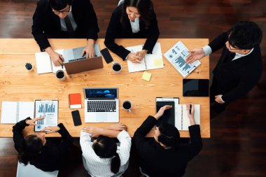 Top view manager or office worker give presentation in harmony conference room to business colleague, BI data dashboard on screen and pile of financial analyzed data reports on meeting table.