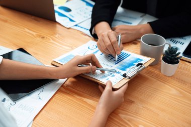 Closeup on BI dashboard on meeting desk with businesspeople analyzing or planning business strategy with hands pointing on financial paper reports as concept of harmony in office workplace.
