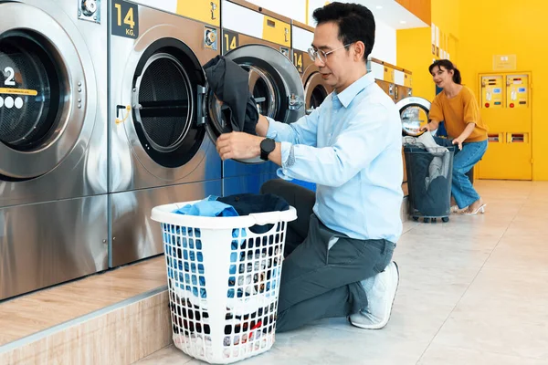 stock image Asian people using qualified coin operated laundry machine in the public room to wash their cloths. Concept of a self service commercial laundry and drying machine in a public room.