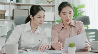 Ofis çalışma alanında birlikte çalışan iki genç hevesli iş kadını. Genç meslektaşlar tartışırken ve dizüstü bilgisayar kullanırken. Modern ofis çalışanları masada birlikte oturuyorlar..