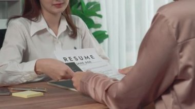 İş yerindeki profesyonel İK müdürüyle yakın çekim genç ve hevesli bir aday görüşmesi. Başvuru sahiplerini inceleyen işveren, iş görüşmesine hazırlanmak üzere işe devam ediyor.