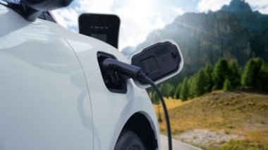 Elektro jeneratör sürücüsüyle enerji sürdürülebilir araba gücü, şarj istasyonunda şarj edilen batarya, ilerici seyahat konsepti için dağ zeminine sahip. Temiz ortamın sembolü olarak doğadaki EV otomobil.