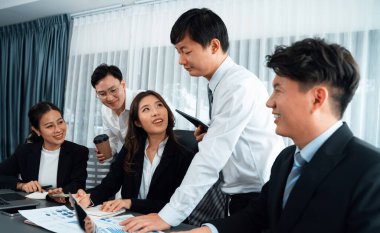 Harmony in office concept as business people analyzing dashboard paper together in workplace. Young colleagues give ideas at manager desk for discussion or strategy planning about project.